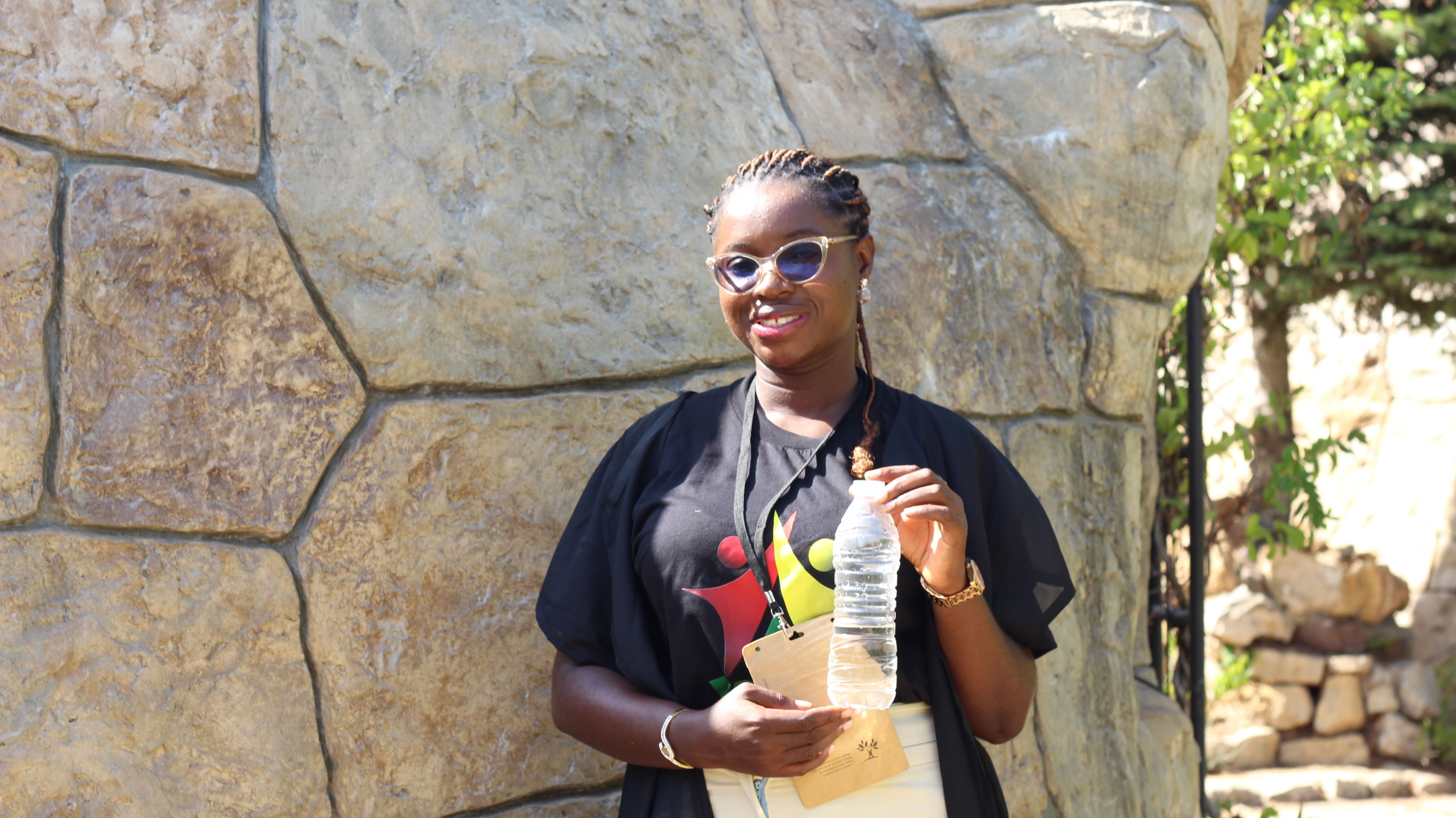A photo of Blessing Ewa holding her object of memory: a plastic water bottle